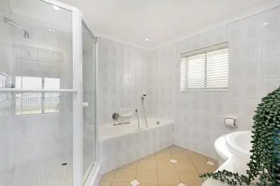 a white bathroom with a shower and a tub at Villa Kyma in Gordonʼs Bay