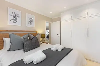 a bedroom with a bed with two towels on it at Villa Kyma in Gordonʼs Bay