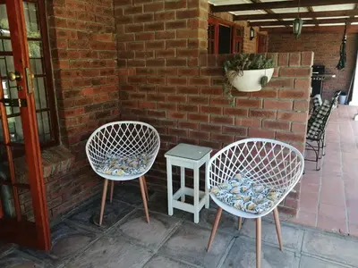 two chairs and a table in front of a brick wall at Gästehaus HelderbergView in Somerset West
