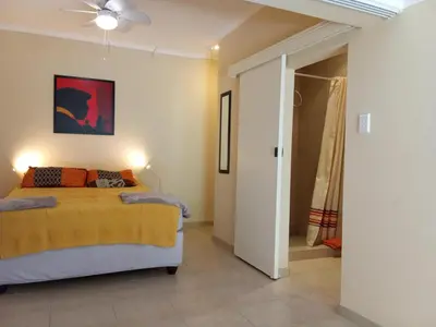 a bedroom with a bed with a yellow blanket at Gästehaus HelderbergView in Somerset West