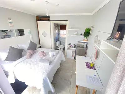 a bedroom with a white bed with a doll on it at Kwaaami in Cape Town