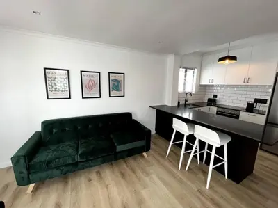a living room with a green couch and a kitchen at Centrally located modern 2-bedroom home & parking in Cape Town