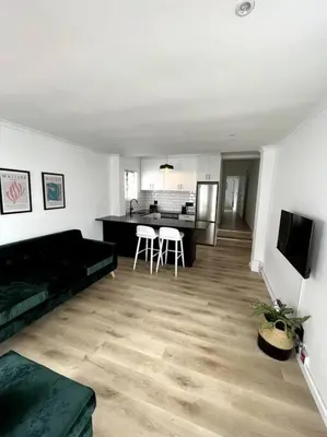 a living room with a black couch and a kitchen at Centrally located modern 2-bedroom home & parking in Cape Town