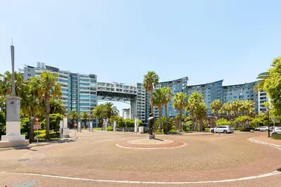a park in front of a large building with palm trees at Knightsbridge 108 in Cape Town
