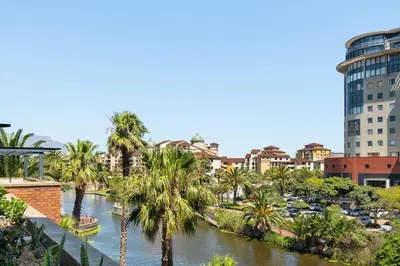 a river in a city with palm trees and buildings at Knightsbridge 108 in Cape Town