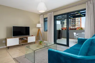 a living room with a blue couch and a tv at Knightsbridge 108 in Cape Town