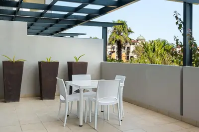 a white table and chairs on a balcony with plants at Knightsbridge 108 in Cape Town