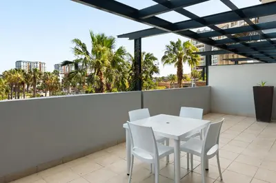 a white table and chairs on a balcony with palm trees at Knightsbridge 108 in Cape Town