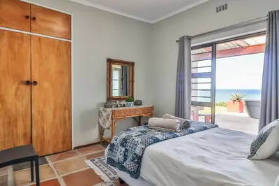 a bedroom with a bed and a mirror and a window at Jock's View in Bettyʼs Bay