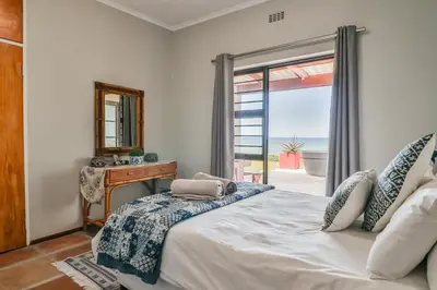 a bedroom with a bed with a view of the ocean at Jock's View in Bettyʼs Bay