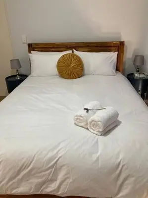 a white bed with two towels on it at Johan-nest in Cape Town