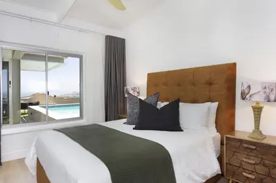 a bedroom with a bed and a large window at Atlantic Sky Villa in Gordonʼs Bay