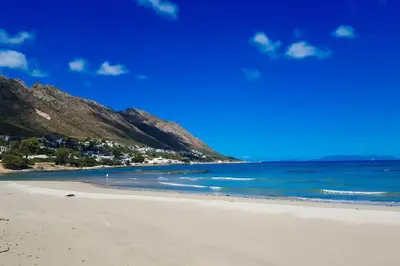 a beach with the ocean and mountains in the background at The Elephant House in Cape Town
