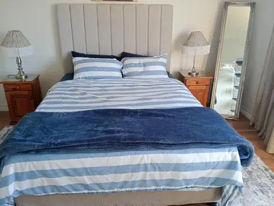 a bed with a blue and white blanket and a mirror at The Wee Hoose in Strand