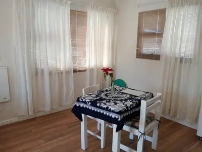 a dining room with a table and chairs and windows at The Wee Hoose in Strand