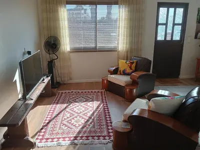 a living room with couches and a television and a rug at The Wee Hoose in Strand