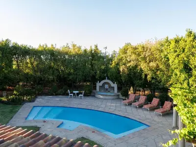 a swimming pool in a yard with chairs and a fountain at Dawn Mountains Farm in Simondium