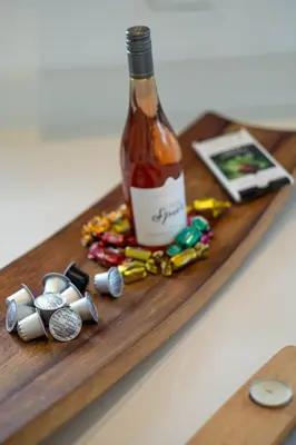 a bottle of alcohol on a wooden table with charms at SAM's - Sea And Mountain in Hermanus