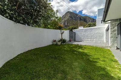 a backyard with a white fence and a green yard at SAM's - Sea And Mountain in Hermanus
