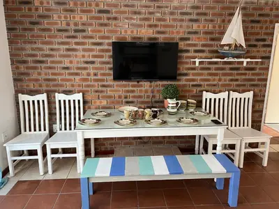 a white table with chairs and a tv on a brick wall at Coastal House: 3BR+Private Entrance+Self catering in Cape Town