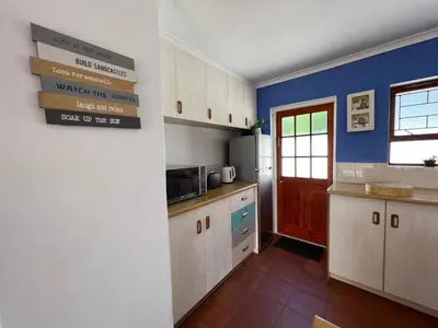 a kitchen with white cabinets and a blue wall at Coastal House: 3BR+Private Entrance+Self catering in Cape Town