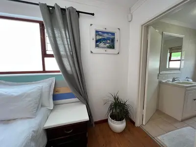 a bedroom with a bed and a sink and a mirror at Coastal House: 3BR+Private Entrance+Self catering in Cape Town
