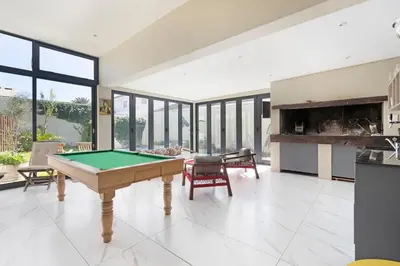 a pool table in a living room with windows at On 8th Green Worthing Villa in Cape Town