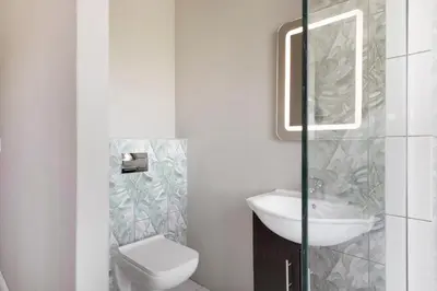a white bathroom with a sink and a toilet at On 8th Green Worthing Villa in Cape Town