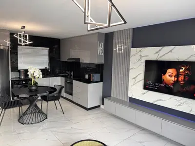 a kitchen with a table and a tv on a wall at Exclusive Ultra-Luxury A Cut Above Apartments Century City by Vvip Bookings in Cape Town