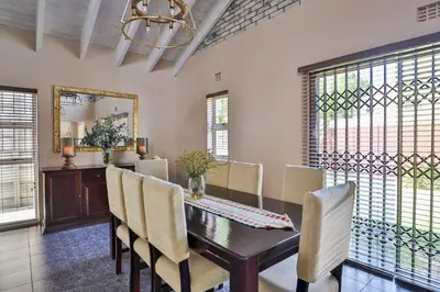 a dining room with a table and chairs and a mirror at Fairview Crescent by CTHA in Cape Town