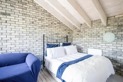 a bedroom with a bed and a brick wall at Fairview Crescent by CTHA in Cape Town