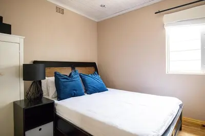 a bedroom with a bed with blue pillows and a window at Fairview Crescent by CTHA in Cape Town