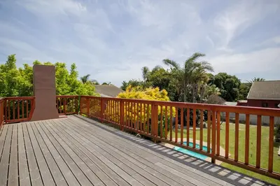 a wooden deck with a fence and a yard at Fairview Crescent by CTHA in Cape Town