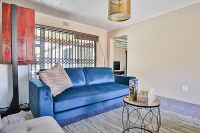 a blue couch in a living room with a table at Fairview Crescent by CTHA in Cape Town