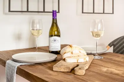 a table with a bottle of wine and two glasses at Avemore Rare Gem with full Backup Power in Stellenbosch