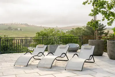 a group of white chairs sitting on a patio at Avemore Rare Gem with full Backup Power in Stellenbosch