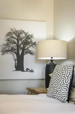 a bed with a lamp and a tree picture on the wall at Avemore Time Out - full power back up in Stellenbosch