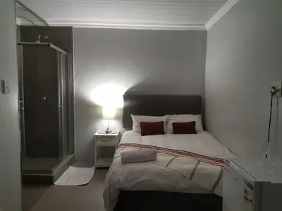 a bedroom with a bed and a glass shower at Maseyi On 8 bnb in Cape Town