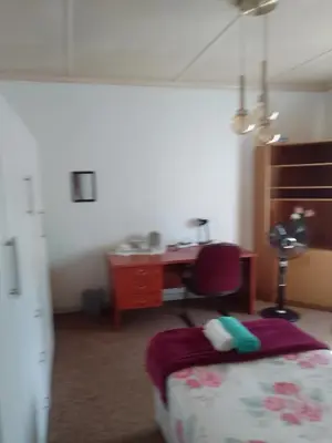 a bedroom with a desk and a bed and a chair at LRN Brackenfell Homestay in Cape Town