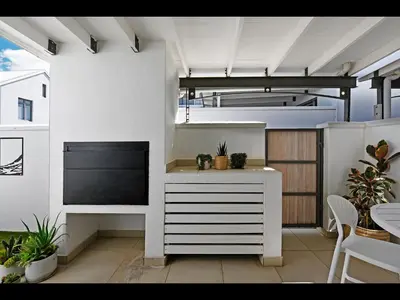 a white kitchen with plants and a table at The Village Cottage in Franschhoek