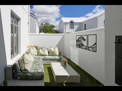 a balcony with a couch and a coffee table at The Village Cottage in Franschhoek