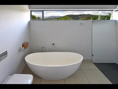 a white bath tub in a bathroom with a window at The Village Cottage in Franschhoek