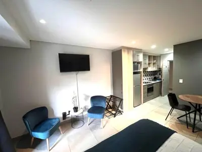 a living room with blue chairs and a table at Modern Apartment in Stellenbosch in Stellenbosch