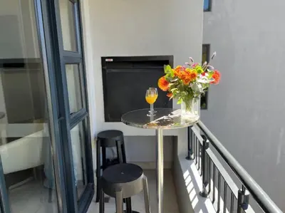 a table with a vase of flowers and a glass of wine at Modern Apartment in Stellenbosch in Stellenbosch