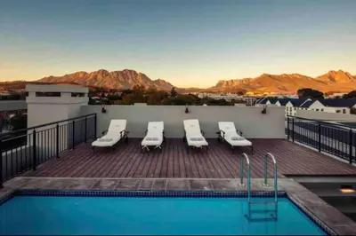 a pool on the roof of a building with mountains at Modern Apartment in Stellenbosch in Stellenbosch