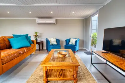 a living room with a brown couch and blue chairs at Magnificent Villa Load-Shedding Free! in Cape Town