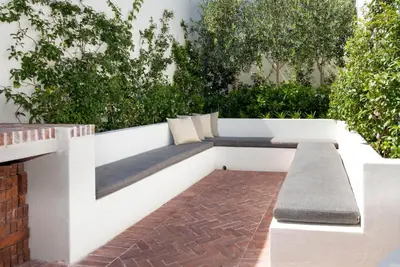 a bench in a garden with trees in the background at Middedorp Manor in Stellenbosch