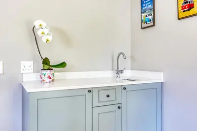 a white kitchen with a sink and a flower in a vase at Loft de L'Opera - Franschhoek in Franschhoek
