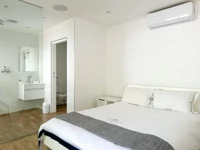 a white bedroom with a bed and a bathroom at Riebeeck Villa - 5 min walk to Franschhoek Central in Franschhoek