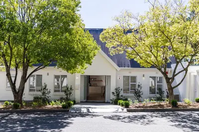 a white house with trees in front of it at Riebeeck Villa - 5 min walk to Franschhoek Central in Franschhoek